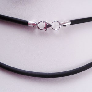 May include: A black rubber necklace with a silver clasp. The necklace is 3mm thick.