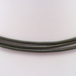 May include: A triple-strand leather necklace in a dark olive green color.