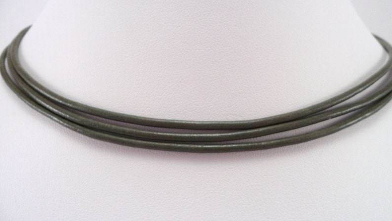 May include: A triple-strand leather necklace in a dark olive green color.