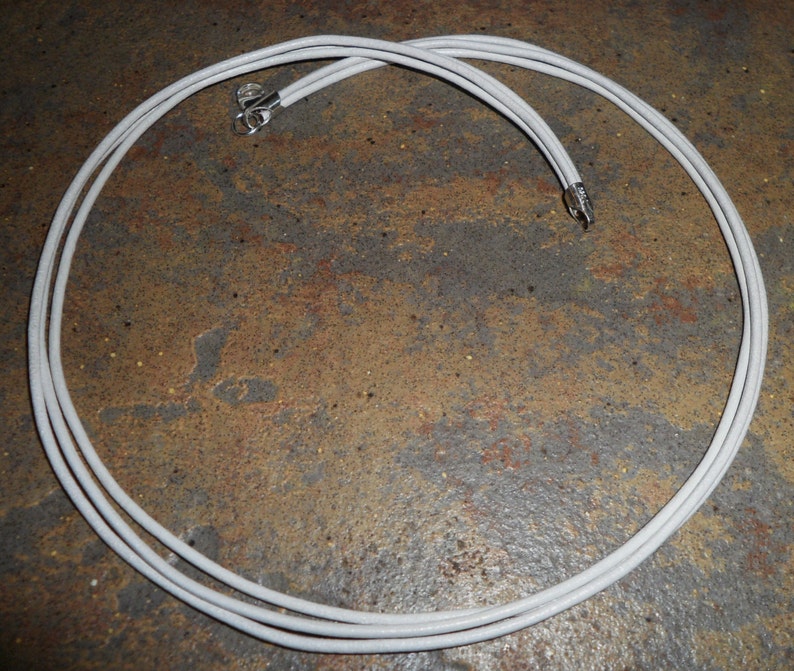 May include: A white cord with two metal ends, coiled into a circle.
