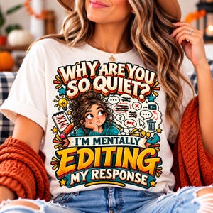 Könnte beinhalten: Ein weißes T-Shirt mit einer bunten Grafik einer Person mit braunen Haaren im Dutt, umgeben von Sprechblasen, einem Notizblock und einem Stift. Der Text lautet: WHY ARE YOU SO QUIET? I'M MENTALLY EDITING MY RESPONSE in fetter, bunter Schrift.