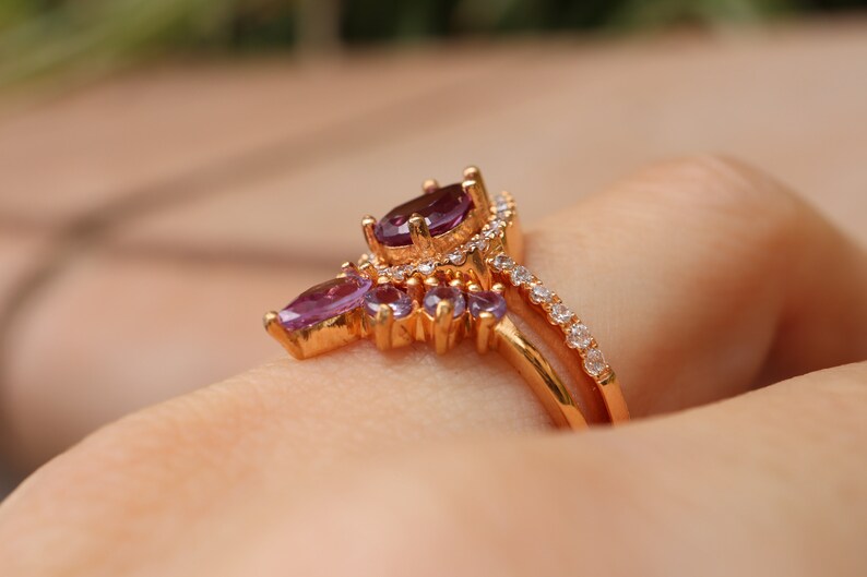 May include: A gold ring with a cluster of purple gemstones and a band of smaller white gemstones.
