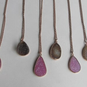 May include: Six delicate gold necklaces with teardrop-shaped pendants. The pendants are made of clear quartz with a sparkly, glittery finish. The quartz comes in a variety of colors, including pink, white, and gray.