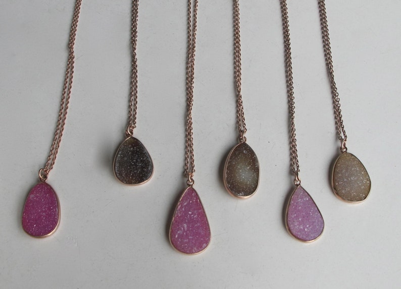 May include: Six delicate gold necklaces with teardrop-shaped pendants. The pendants are made of clear quartz with a sparkly, glittery finish. The quartz comes in a variety of colors, including pink, white, and gray.