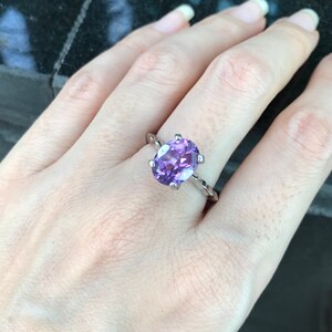 May include: A silver ring with a large oval amethyst gemstone. The ring has a twisted band.