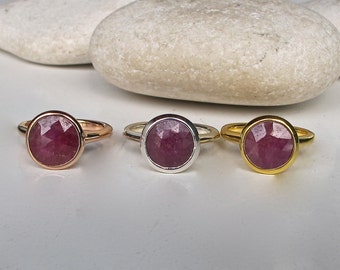 Peut inclure: Trois bagues avec une pierre précieuse ronde et facetée de couleur rose sertie dans un sertissage à bélière. Les bagues sont présentées sur un fond blanc. Les bagues sont disponibles en or, argent et or rose.