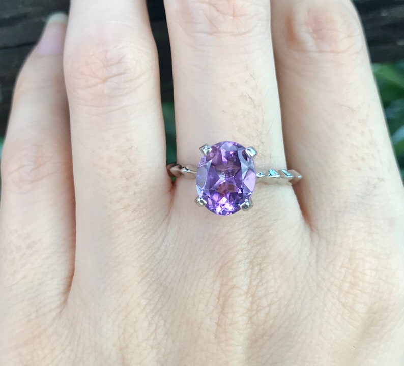 May include: A silver ring with a large oval amethyst gemstone. The ring has a twisted band.