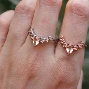 May include: Two gold rings with pear-shaped gemstones and smaller round gemstones set in a curved design.