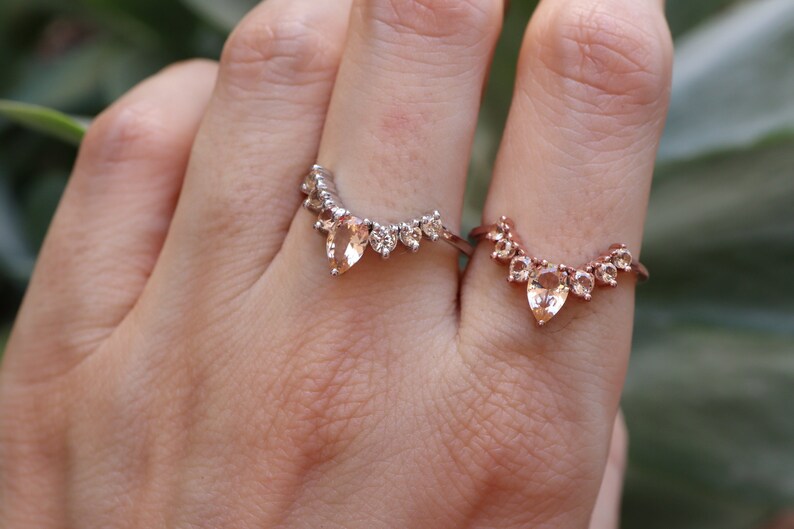May include: Two gold rings with pear-shaped gemstones and smaller round gemstones set in a curved design.