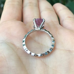 May include: A silver ring with a textured band and a large, purple gemstone.