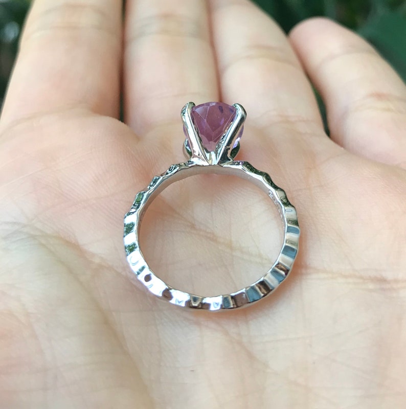May include: A silver ring with a textured band and a large, purple gemstone.
