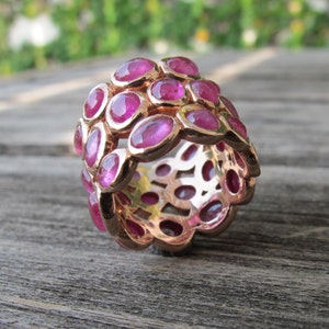 May include: A rose gold ring with a cluster of pink gemstones. The ring is made of multiple bands with a delicate design.