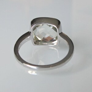 May include: A silver ring with a clear, square-shaped gemstone.