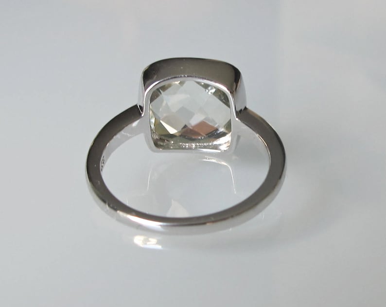 May include: A silver ring with a clear, square-shaped gemstone.