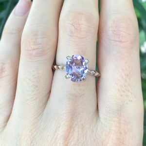 May include: A silver ring with a twisted band and a large, round, light purple amethyst gemstone.