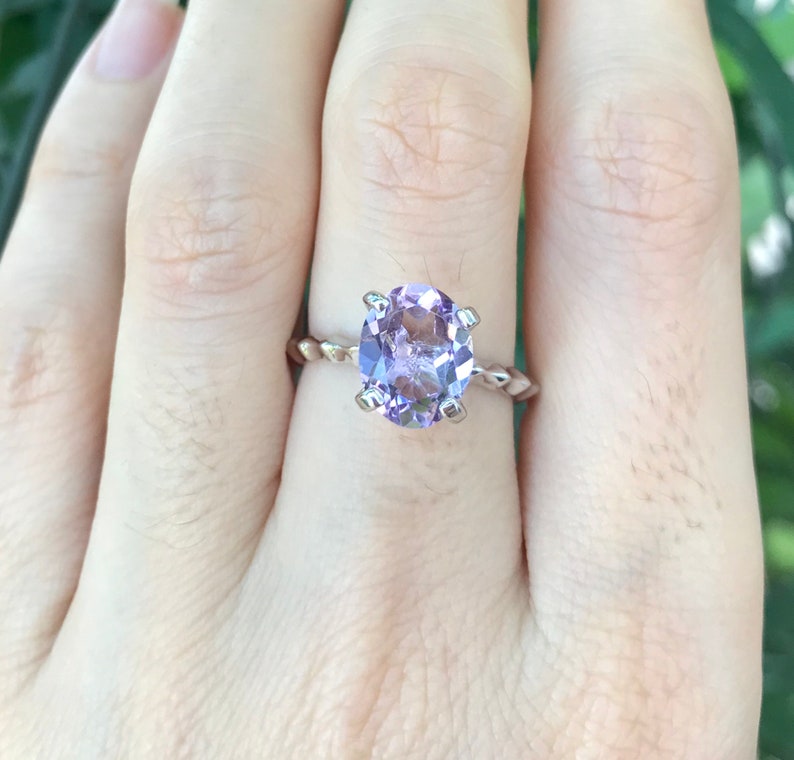 May include: A silver ring with a twisted band and a large, round, light purple amethyst gemstone.