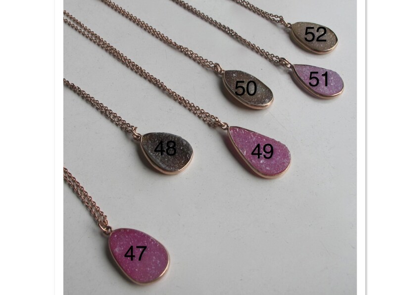 May include: Five silver necklaces with teardrop-shaped pendants. The pendants are made of different types of agate and are numbered 47 through 52.