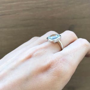 May include: A silver ring with a large, clear, cushion-cut gemstone.
