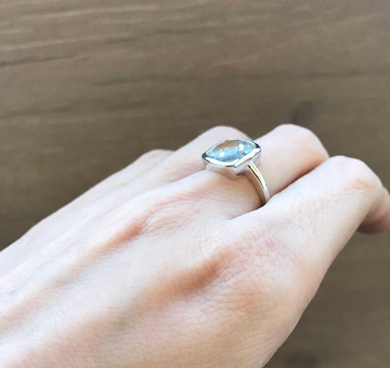 May include: A silver ring with a large, clear, cushion-cut gemstone.