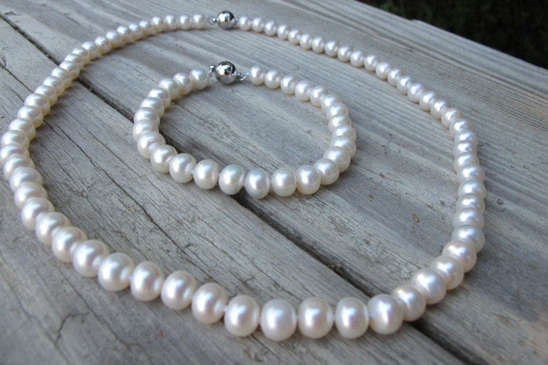 May include: A set of white pearl jewellery, comprising a necklace and a bracelet. Both pieces feature a classic design with a simple string of pearls.