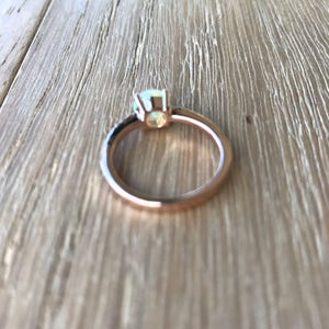 Pode incluir: Um anel de ouro rosa com uma pedra de opala branca e diamantes negros engastados em pav&eacute;.