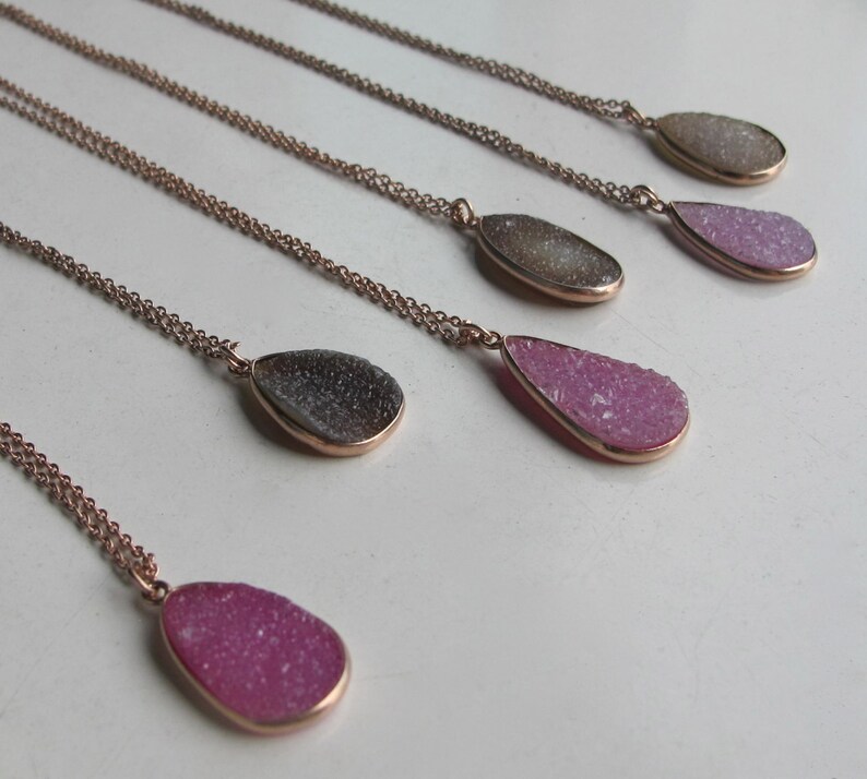 May include: Five gold necklaces with teardrop-shaped pendants made of clear, pink, and gray crystal.