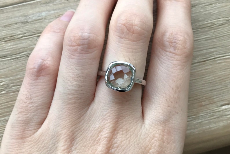 Puede incluir: Un anillo de plata con una piedra preciosa cuadrada de color verde claro.