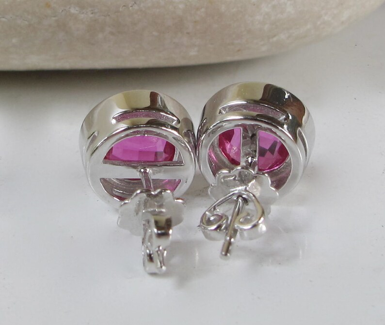 Puede incluir: Un par de pendientes de plata con piedras ovaladas de color rosa.