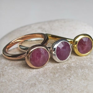 May include: Three rings with pink gemstone settings. The rings are made of gold, silver, and rose gold.