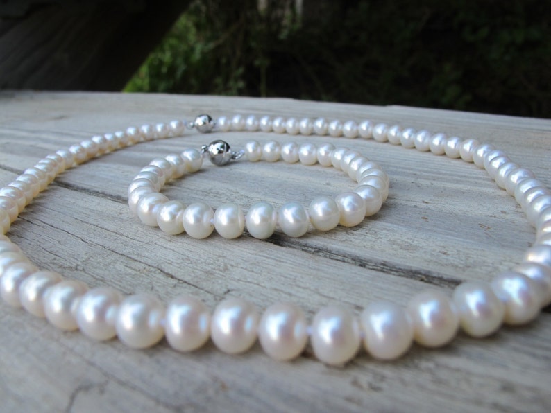 May include: A set of white pearl jewellery, comprising a necklace and a bracelet. The pearls are strung on a silver chain with a magnetic clasp.