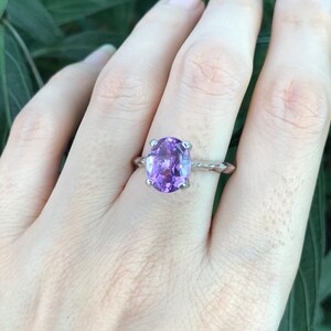 May include: A silver ring with a large oval amethyst gemstone. The ring has a twisted band.