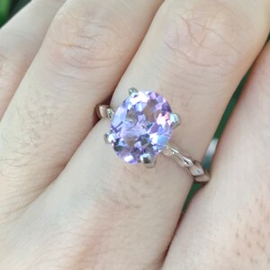 May include: A silver ring with a large oval-shaped amethyst gemstone. The ring has a twisted band.