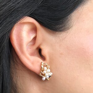 May include: Gold earrings with a cluster of white pearls and a small blue stone.