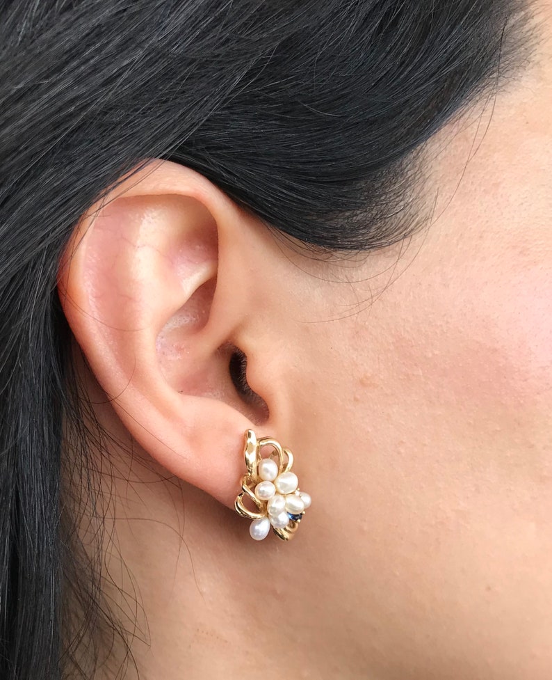 May include: Gold earrings with a cluster of white pearls and a small blue stone.