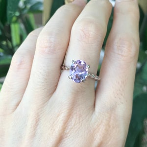 May include: A silver ring with a twisted band and a large oval amethyst gemstone.