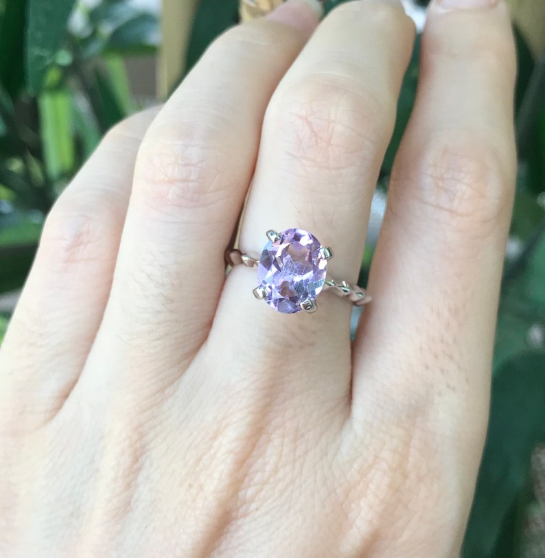 May include: A silver ring with a twisted band and a large oval amethyst gemstone.