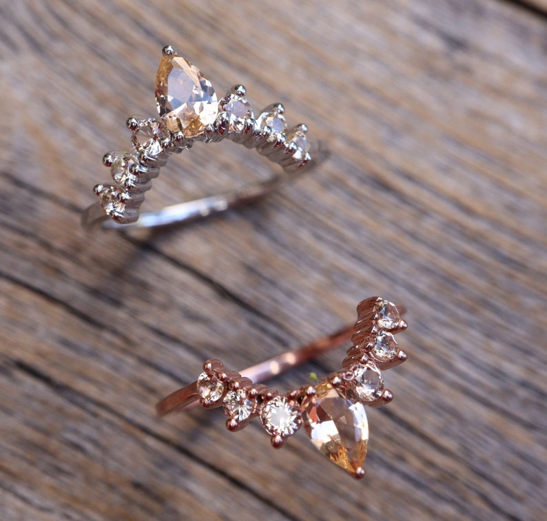 May include: Two delicate rings with a pear-shaped gemstone and smaller round stones. The rings are made of silver and rose gold.