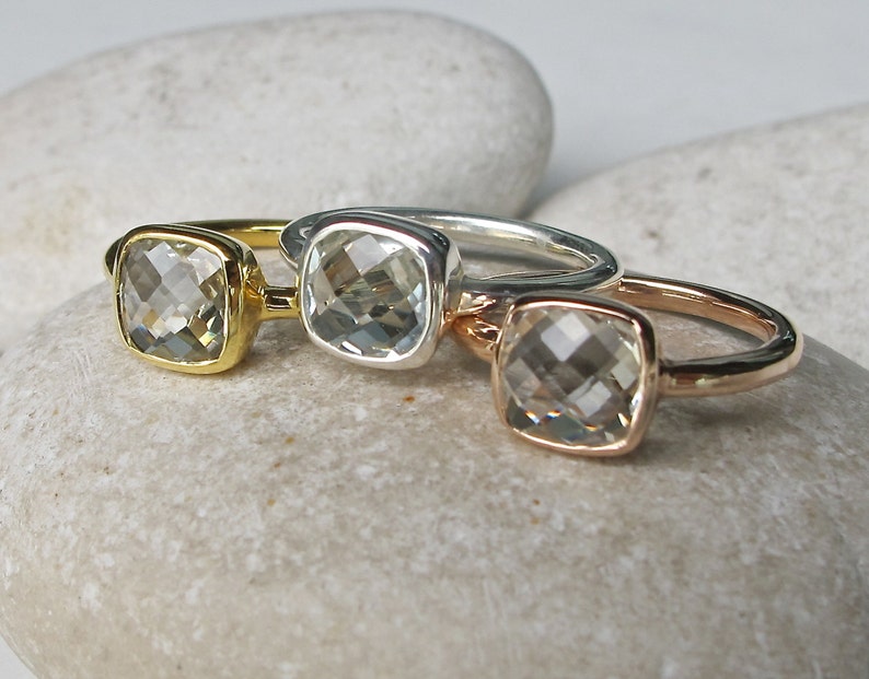 Puede incluir: Tres anillos con piedras preciosas cuadradas transparentes engastadas en bandas de oro, plata y oro rosa.