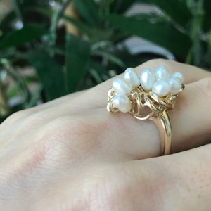 May include: A gold ring with a cluster of white pearls set in a delicate, organic design.