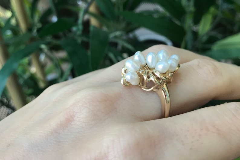 May include: A gold ring with a cluster of white pearls set in a delicate, organic design.