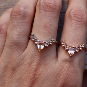 May include: Two gold rings with pear-shaped gemstones and smaller round gemstones set in a V-shape.