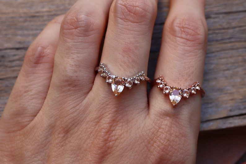 May include: Two gold rings with pear-shaped gemstones and smaller round gemstones set in a V-shape.