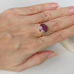 Pu&ograve; includere: Un anello in oro rosa con un grande rubino rotondo sfaccettato.