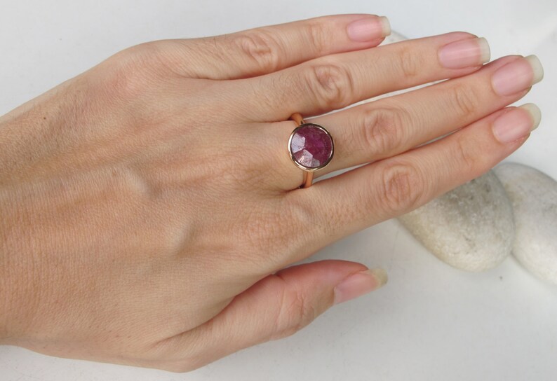 Pu&ograve; includere: Un anello in oro rosa con un grande rubino rotondo sfaccettato.