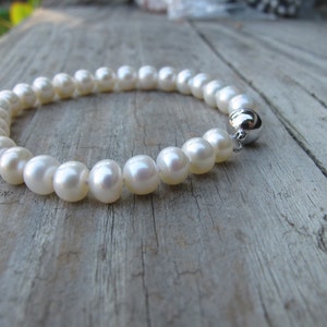 May include: A white pearl bracelet with a silver clasp.