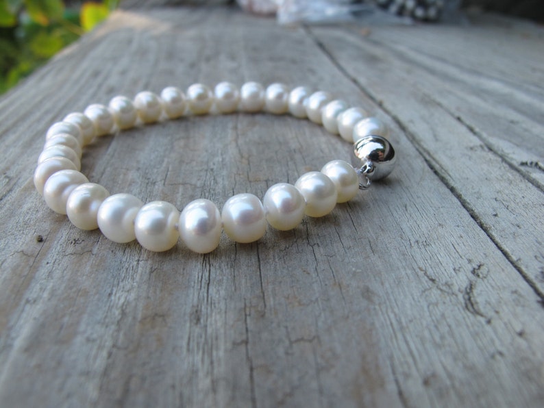 May include: A white pearl bracelet with a silver clasp.