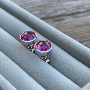 Puede incluir: Un par de pendientes de plata con piedras preciosas rosas. Los pendientes est&aacute;n en una caja de terciopelo.