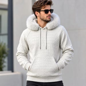 May include: A light grey hoodie featuring a textured crocodile skin pattern throughout the fabric. The garment includes a hood trimmed with thick, fluffy light grey faux fur, long sleeves with ribbed cuffs, a front kangaroo pocket, and drawstrings.