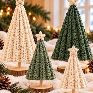 Puede incluir: Cuatro árboles de ganchillo en forma de cono en color crema y verde oscuro, cada uno rematado con una pequeña estrella de ganchillo crema. Los árboles están montados sobre varillas de madera clara y bases circulares de madera.