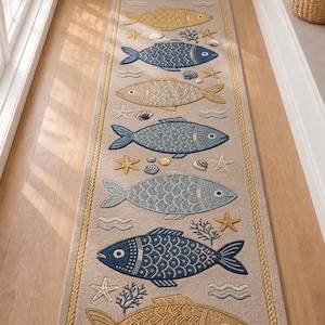 Peut inclure: Un long tapis de couloir rectangulaire de couleur beige clair orné d'un motif répétitif de poissons dans des tons bleu et doré. Le design comprend des étoiles de mer, des coquillages et du corail, le tout encadré par une bordure jaune tressée.